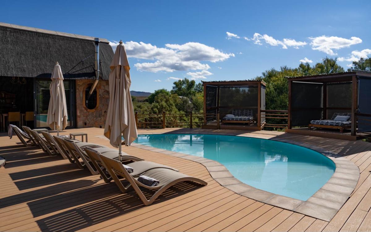 La piscine de Mont Eco avec des chaises longues et des matelas de soleil